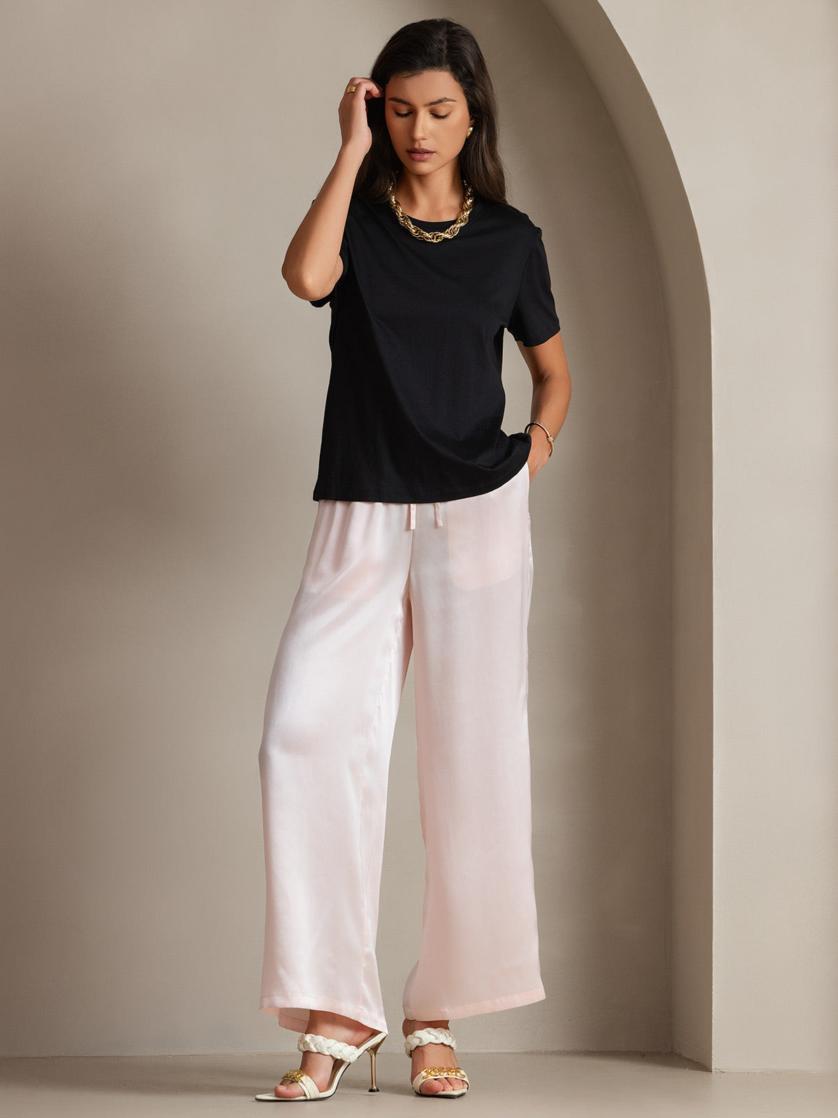 A woman wearing wide-leg crepe pants with a tucked silk tee